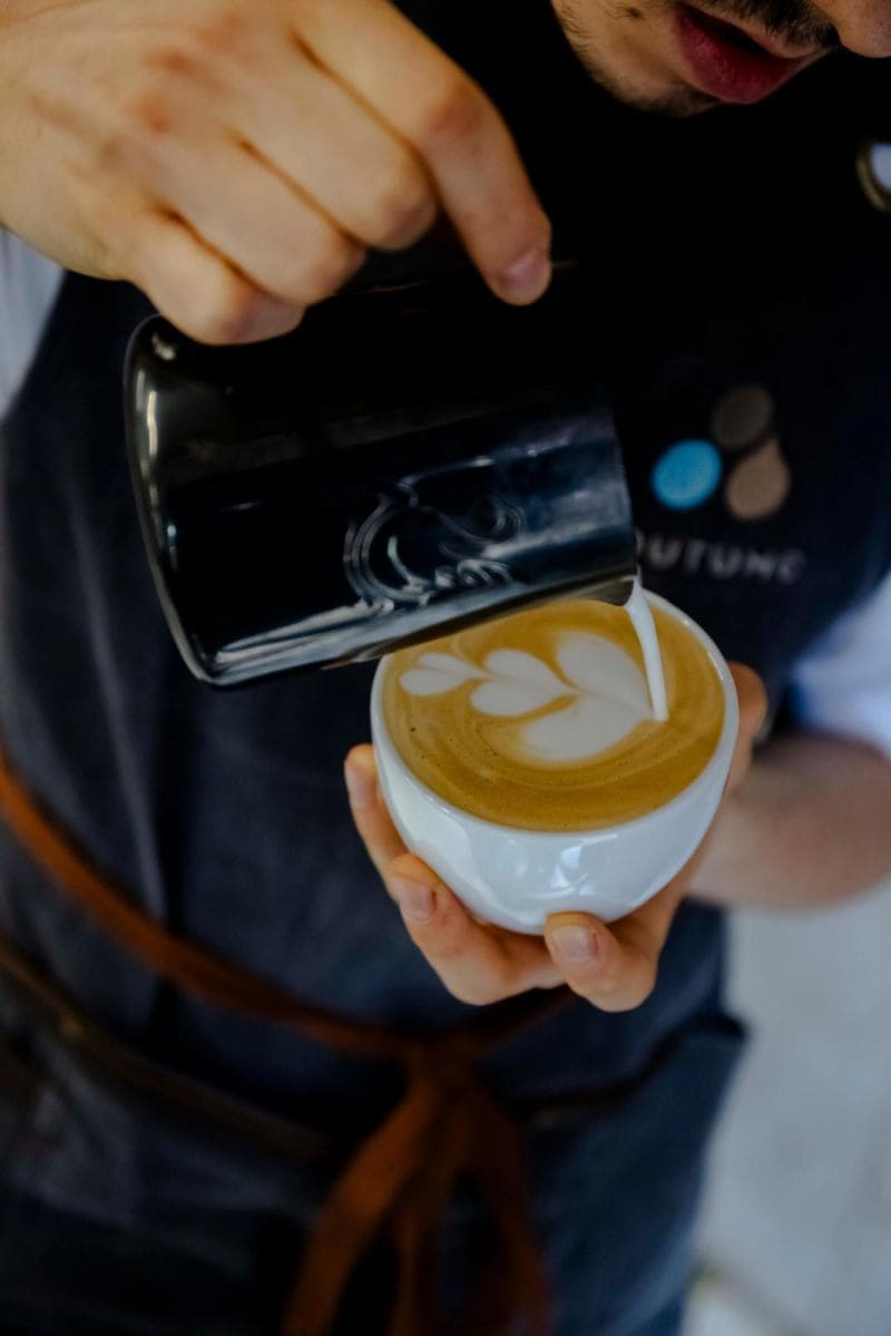 Un barista se concentre sur la préparation méticuleuse d'un café filtre à l'aide d'une bouilloire de précision et d'un porte-filtre manuel.