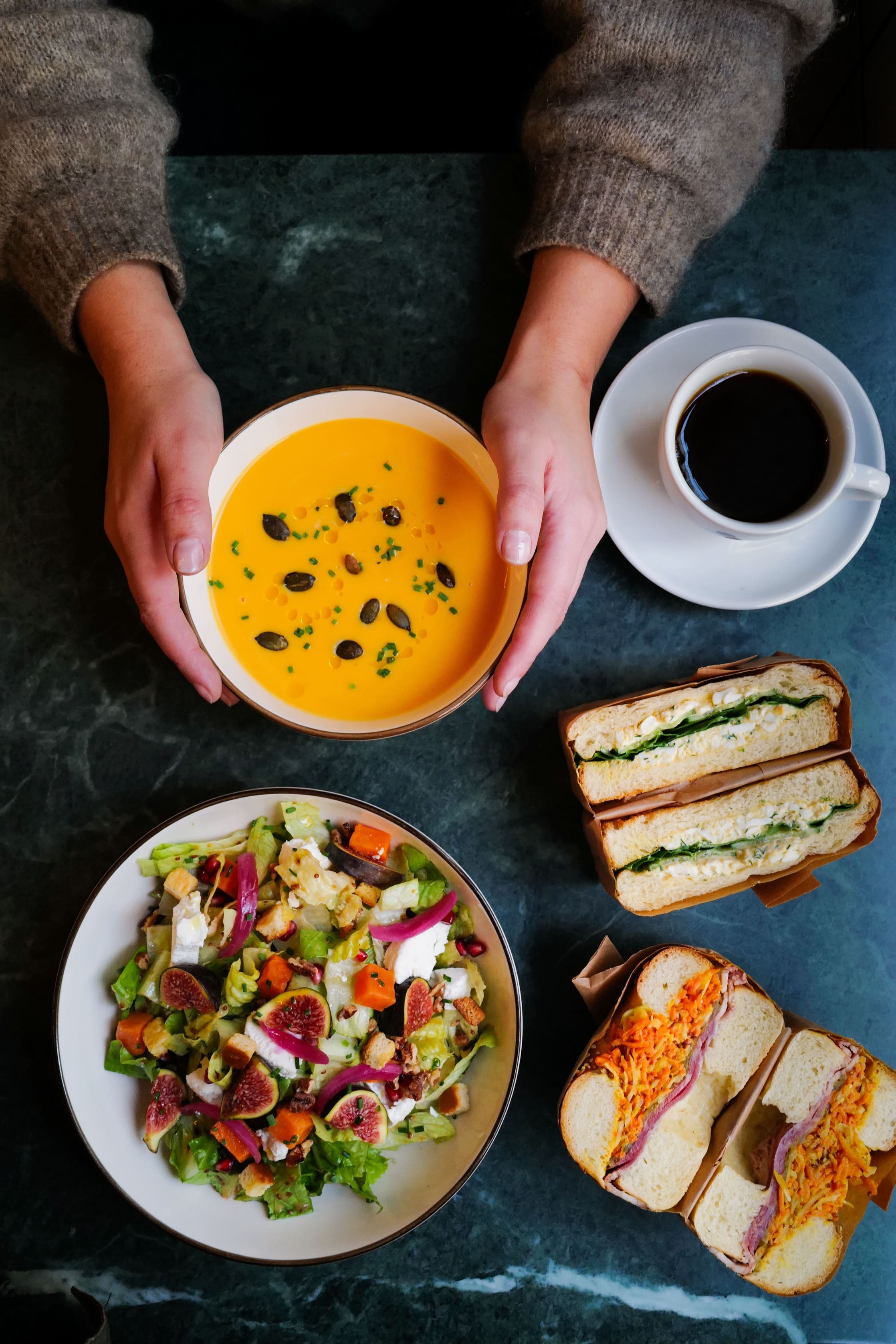 Vue de haut sur un brunch composé de salades et sandwichs